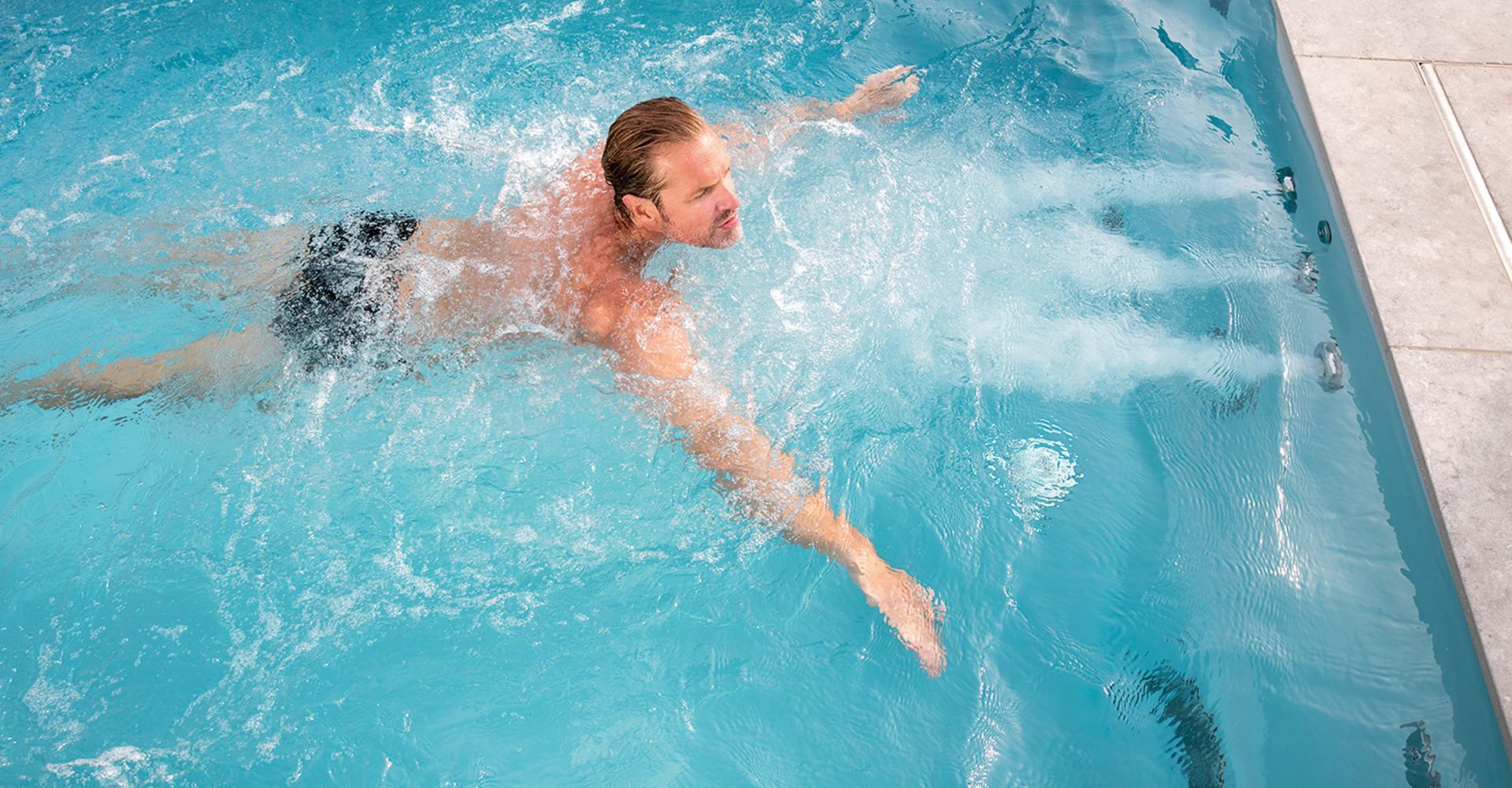 Mann schwimmt im Pool mit Düsen